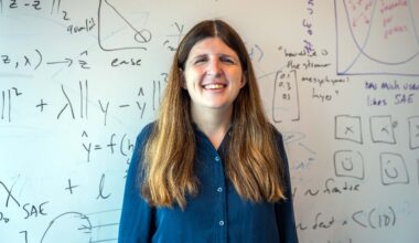 Emma Pierson stands in front of a white board that is covered in mathematical equations.