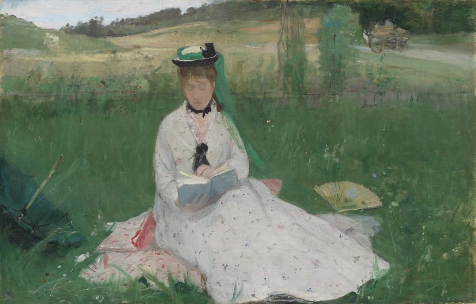 A woman in a white dress and hat sits on the grass reading a book, with a parasol and fan nearby in a green, rural outdoor setting.