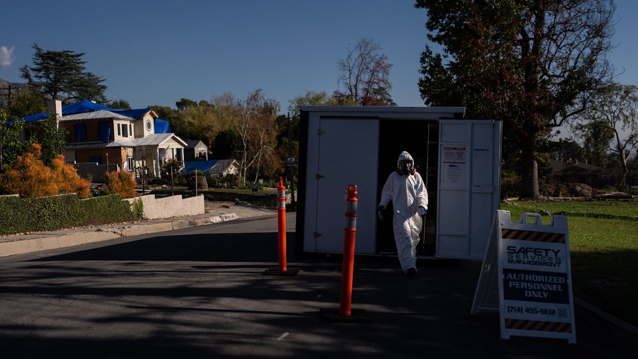 A worker in protective gear exits a storage container at a cleanup site, Dec. 3, 2025, months after the Eaton Fire, in Altadena, Calif. (AP Photo/Jae C. Hong)