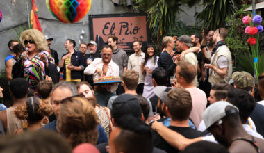 Crowd mingling on a bar's outdoor patio. A pink sign in the back reads, "El Rio."