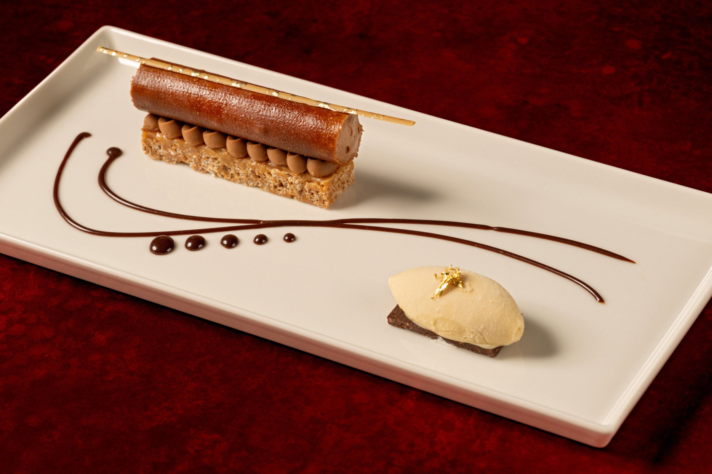 Chocolate bar on a white plate with a decorative string of chocolate and quenelle of ice cream at Napa Rose.