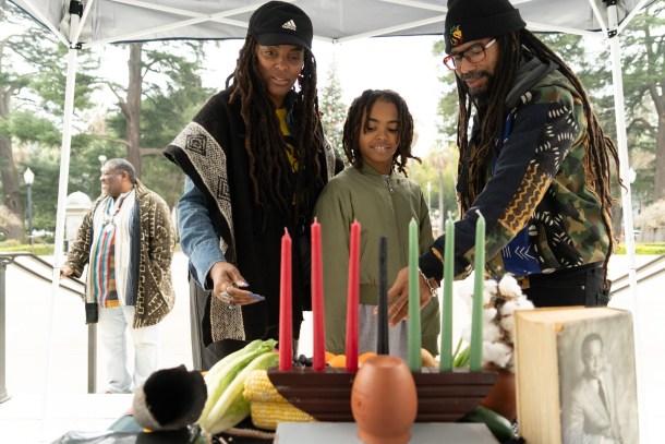 Vanessa, left, and Nestor Hatuey share symbolic elements of Kwanzaa with their son, Bakari, 9. Roberta Alvarado, OBSERVER