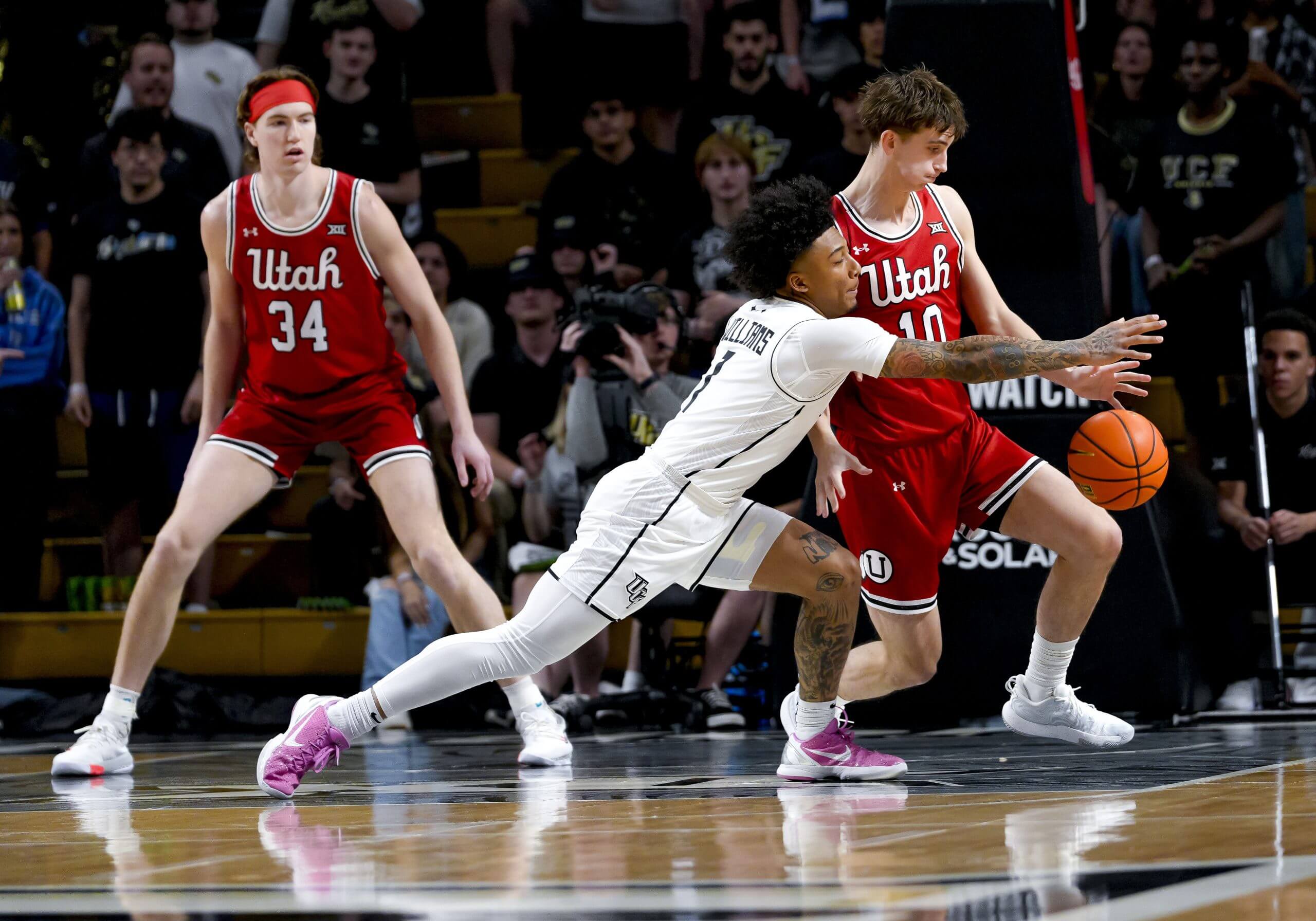Mikey Williams, in white, leans against a Utah player in red, reaching across him for the basketball