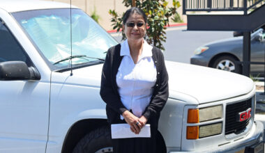 A photo of a woman standing outside by a truck.