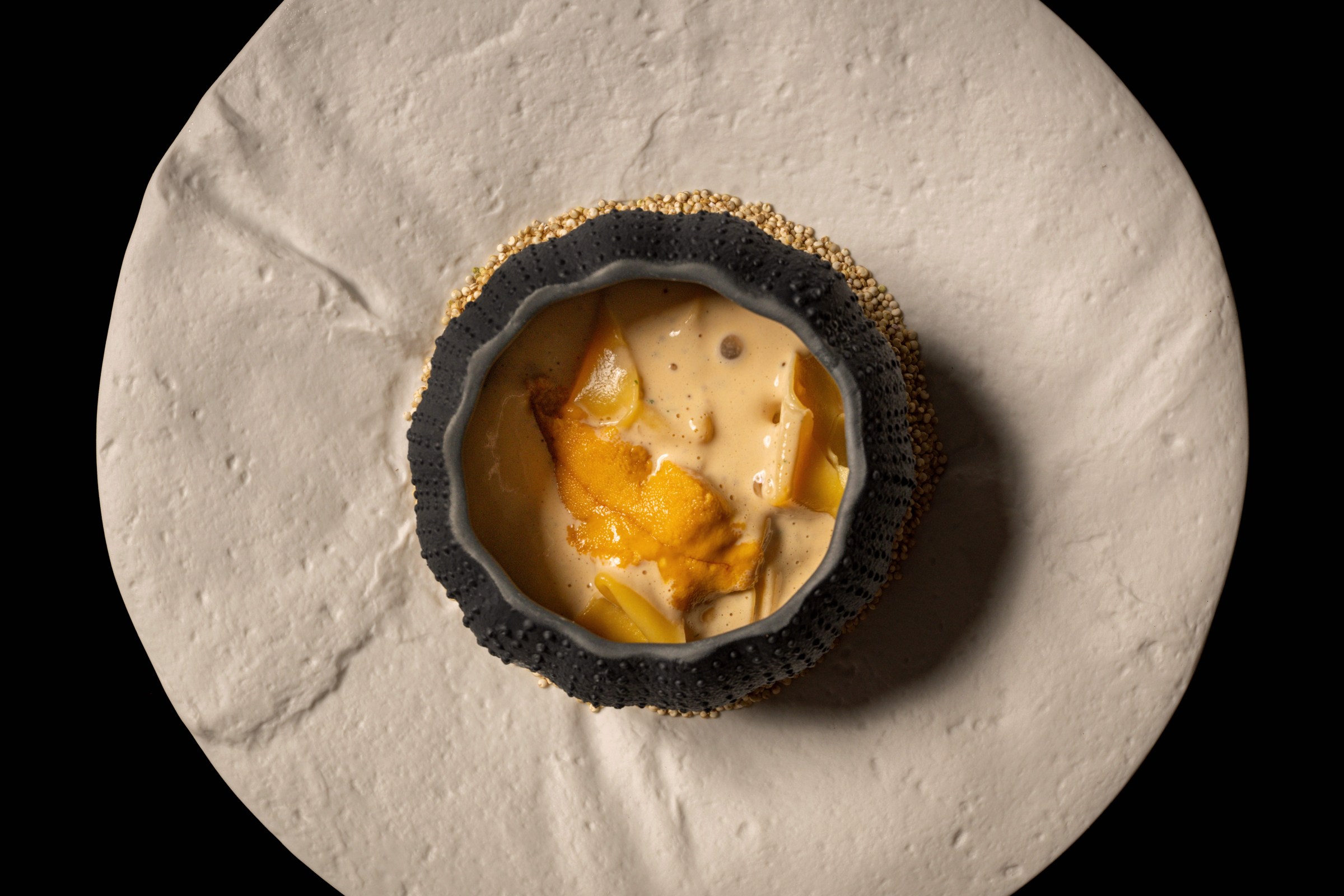 Pasta in a round vessel with uni butter and crab sitting on a marble table at Napa Rose.