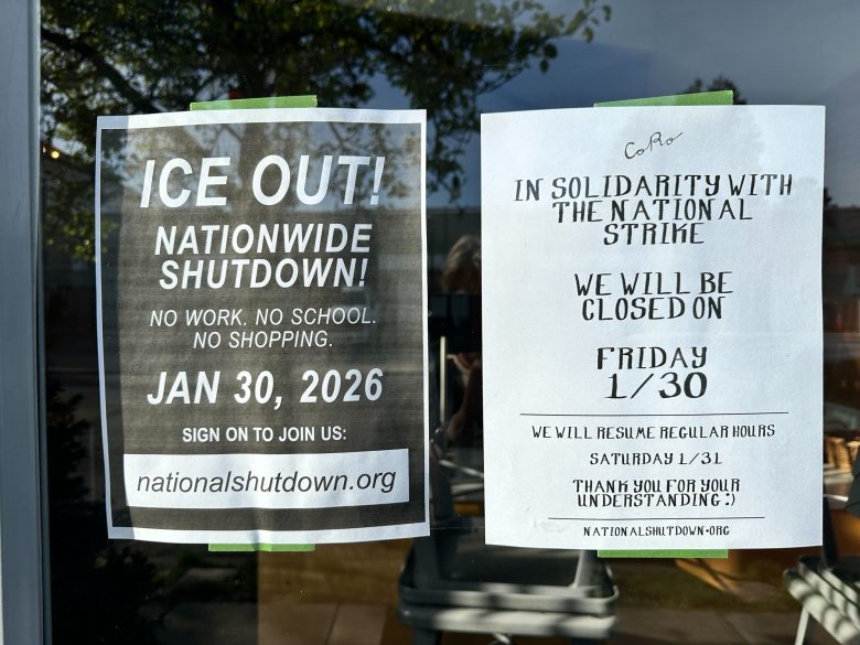 Two pieces of paper are posted in a glass wind, one of which says "ICE Out" in large letters, the other saying the cafe is closed in solidarity with a general strike.