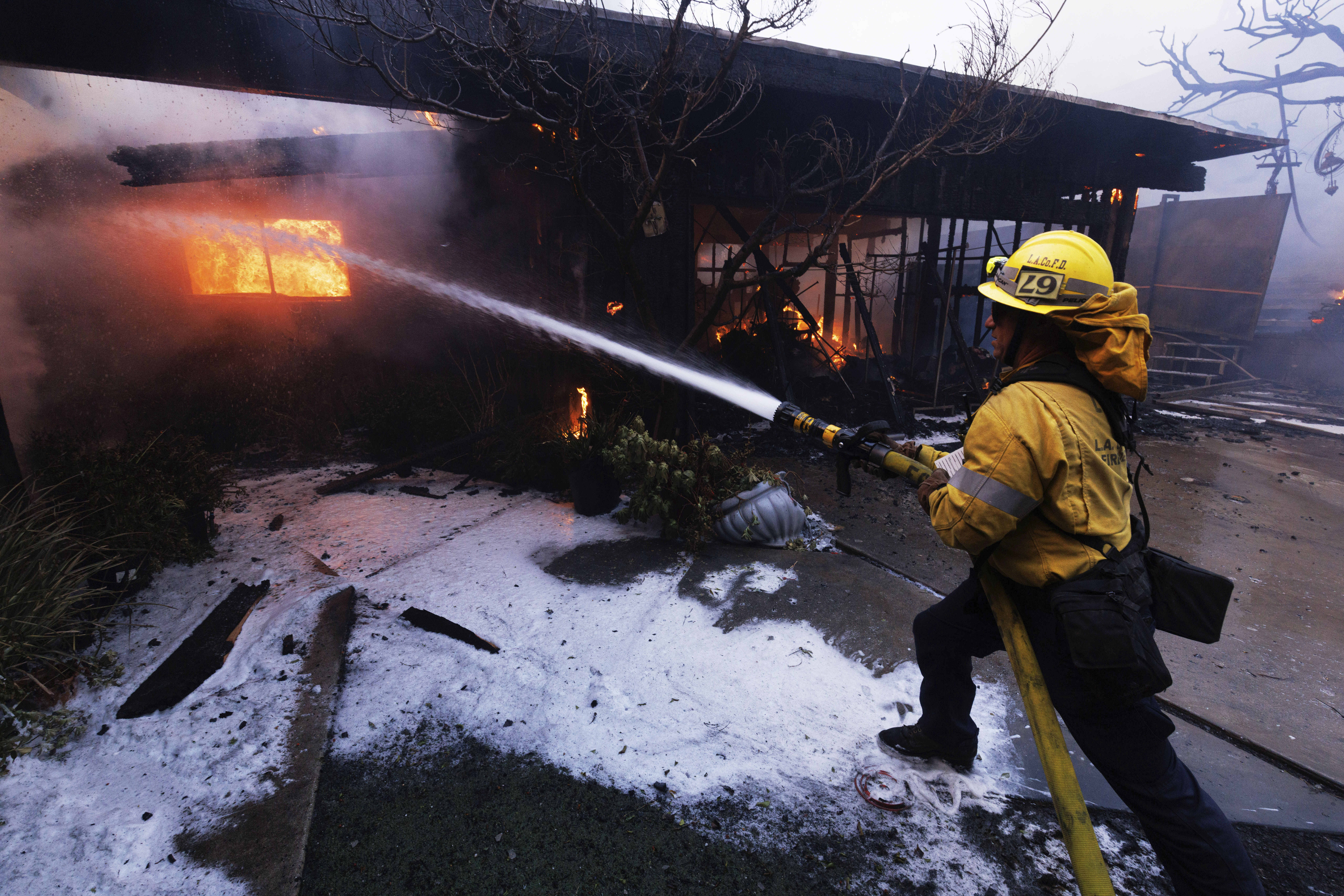 A firefighter tries to extinguish flames in the Pacific Palisades...