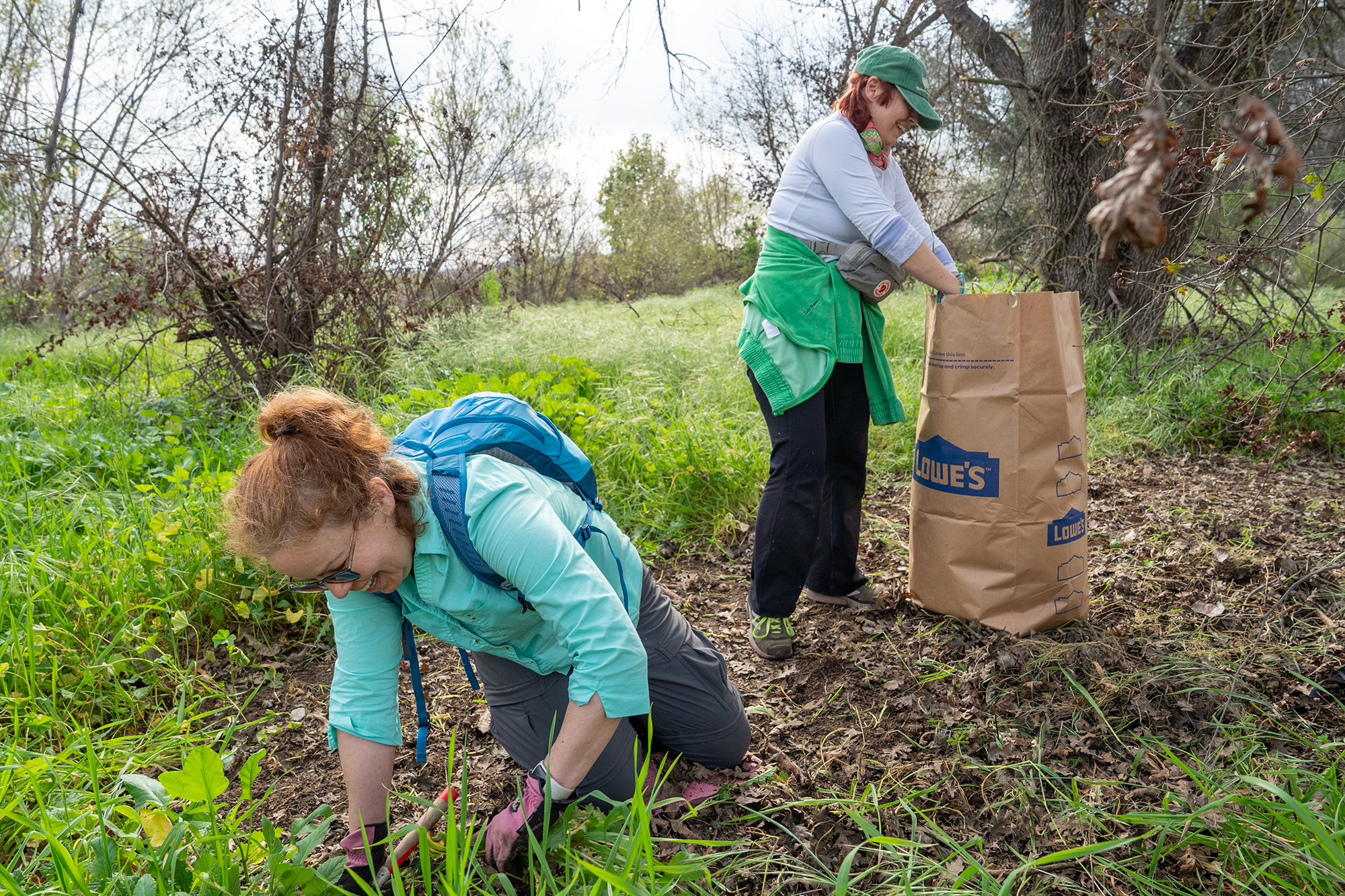 Volunteers Alicia Kozikowski, left, and Martti Nelson remove invasive plants...