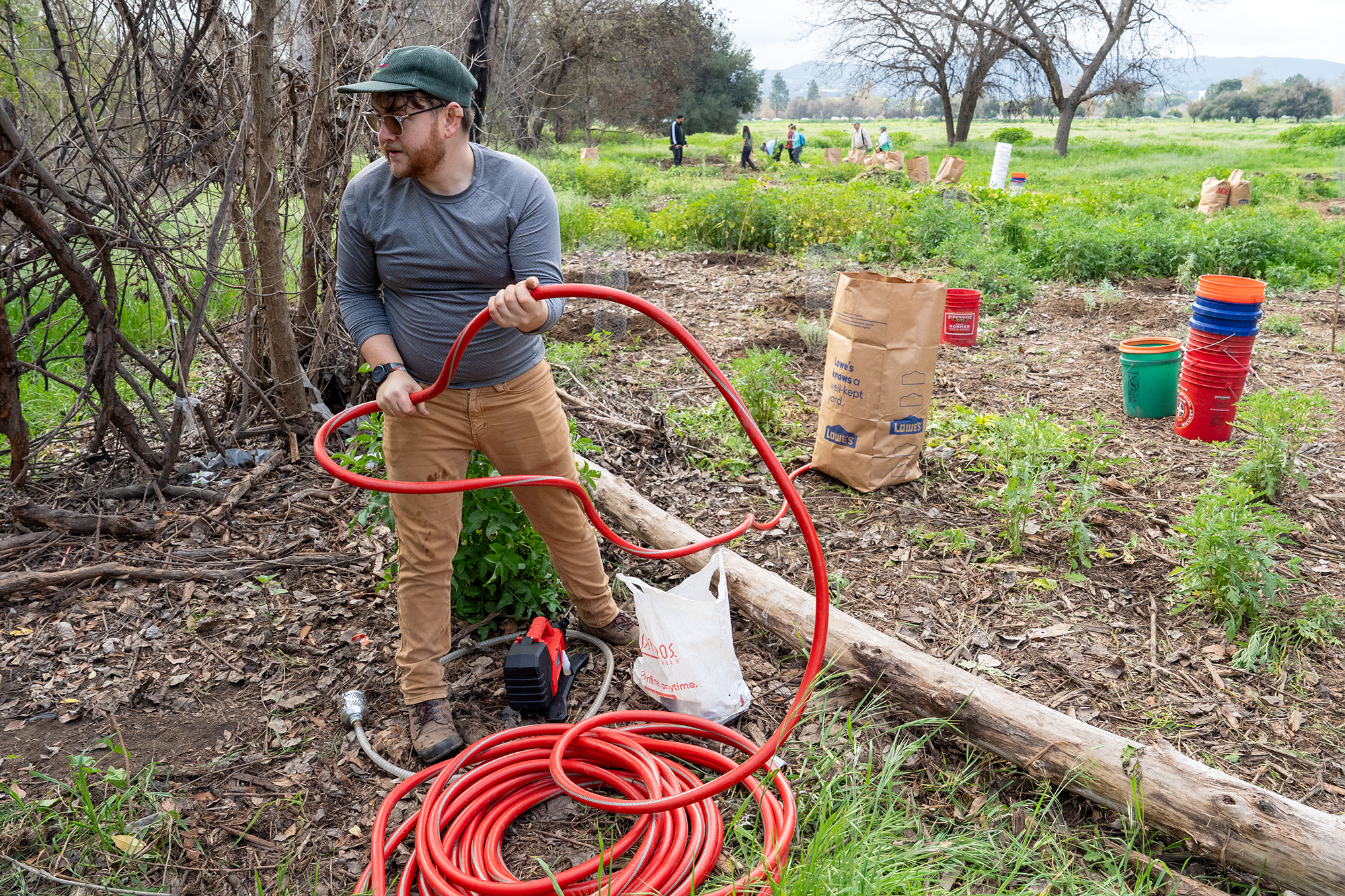 Volunteer Ben Parnas wraps up a hose used to siphon...