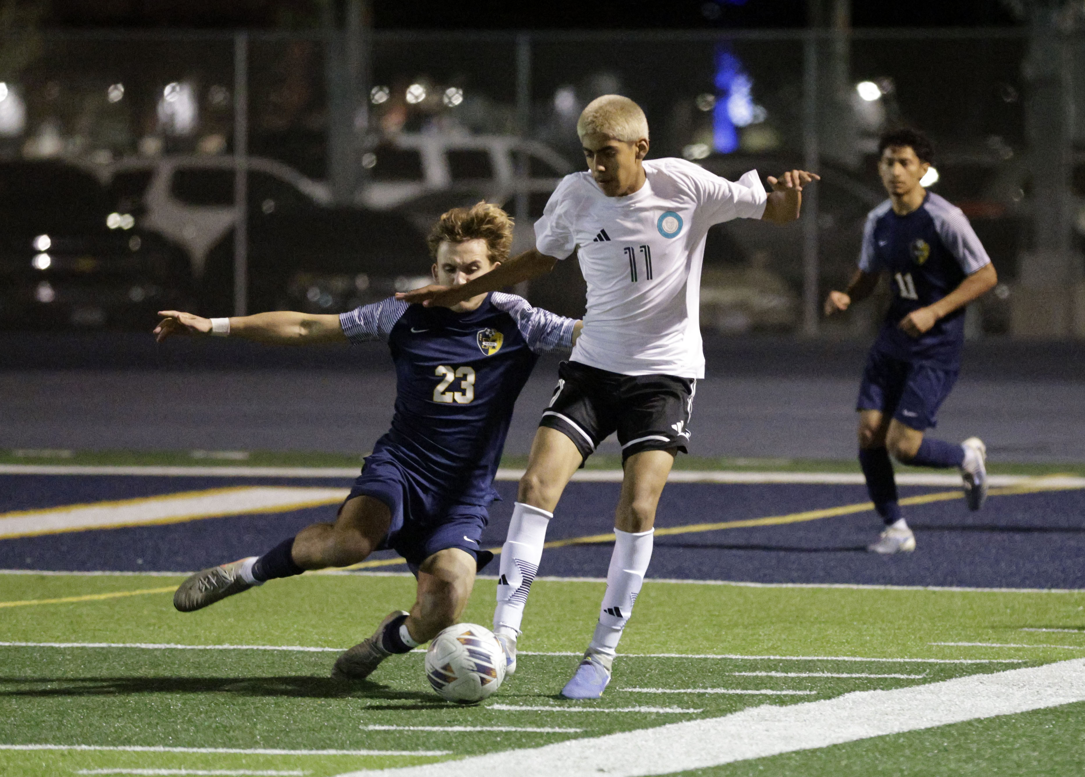 Millikan’s Grant Johnson (23) tries to kick the ball away...