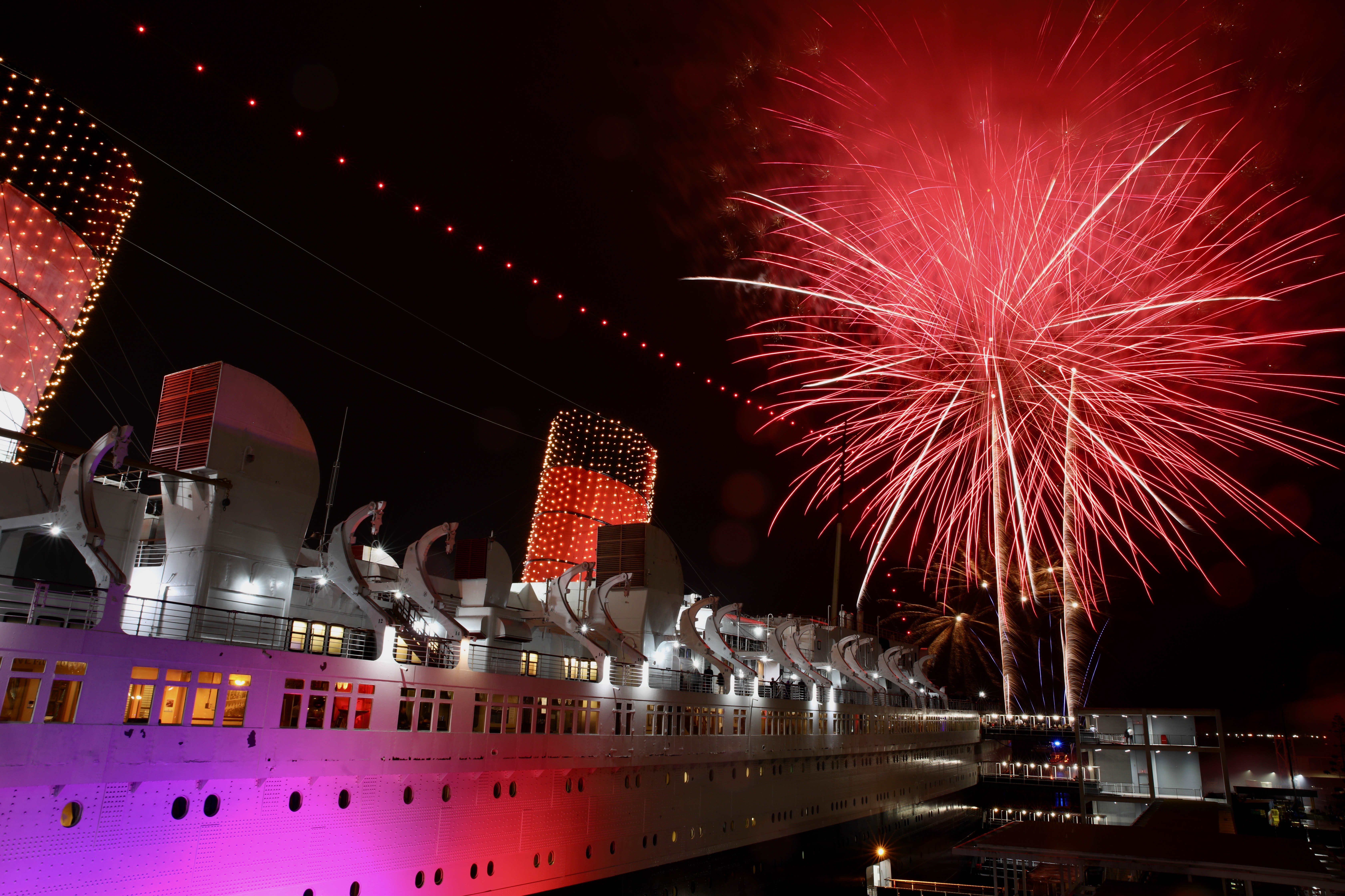 Fireworks light the sky over the Long Beach harbor at...