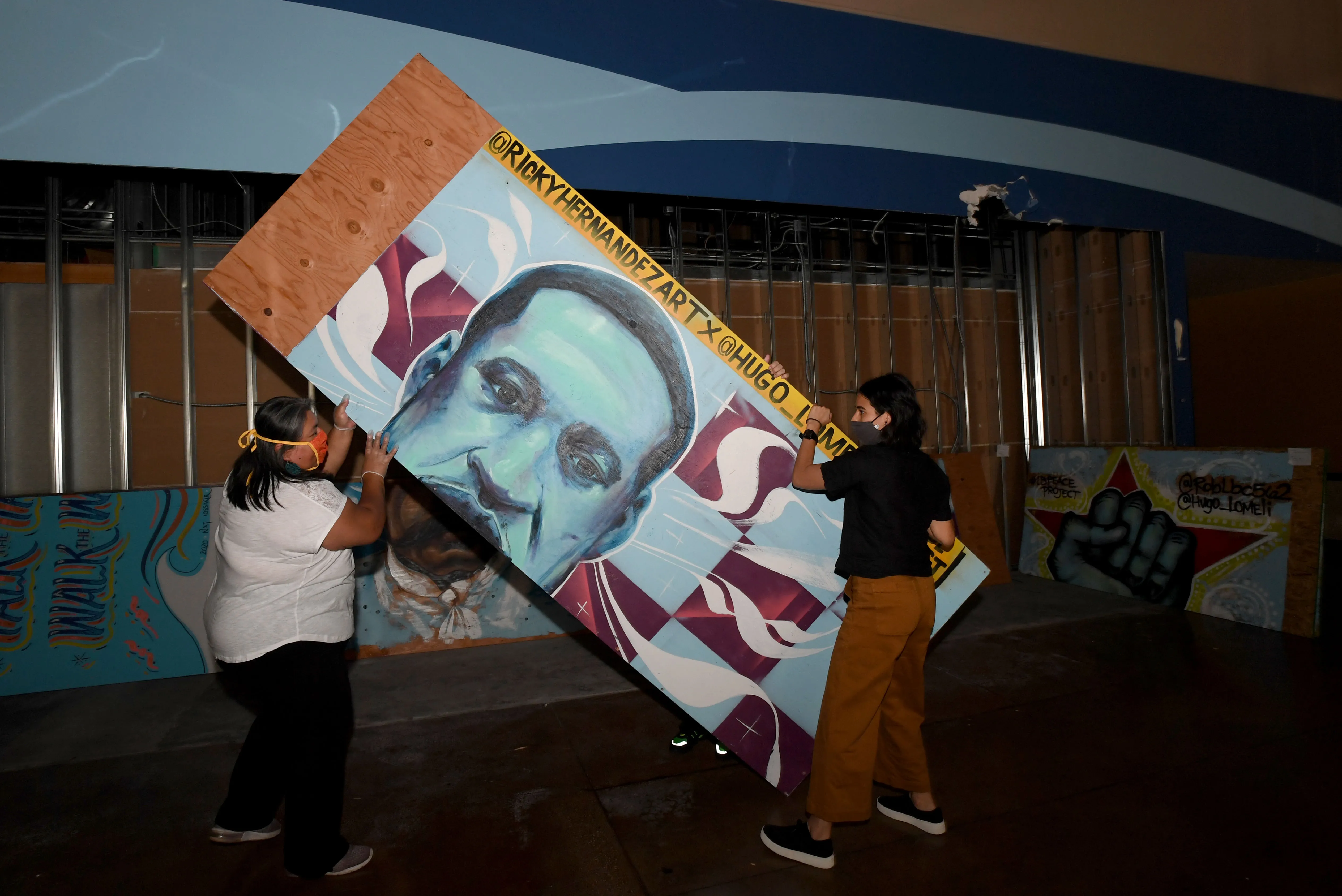 L-R Griselda Suarez and Mariah Hoffman move a protest mural...