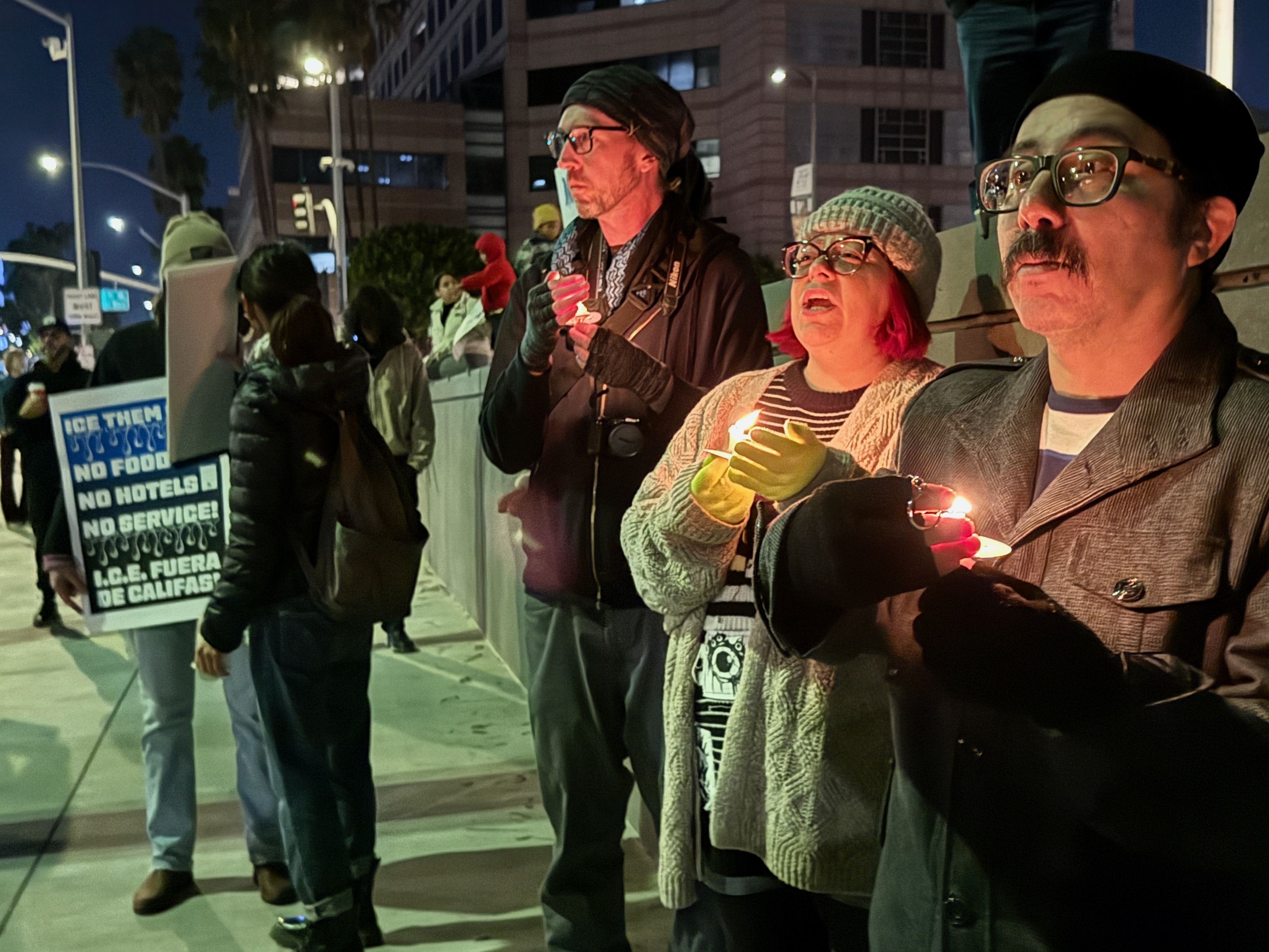 Mourners hold candles near Long Beach City Hall on Thursday,...