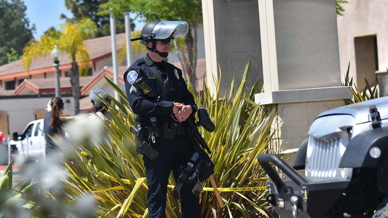 A Coronado police officer stands guard outside the La Mesa Police Department as repairs were made by area volunteers Sunday morning