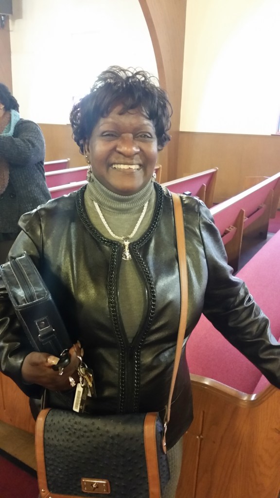 A smiling woman stands amid pews