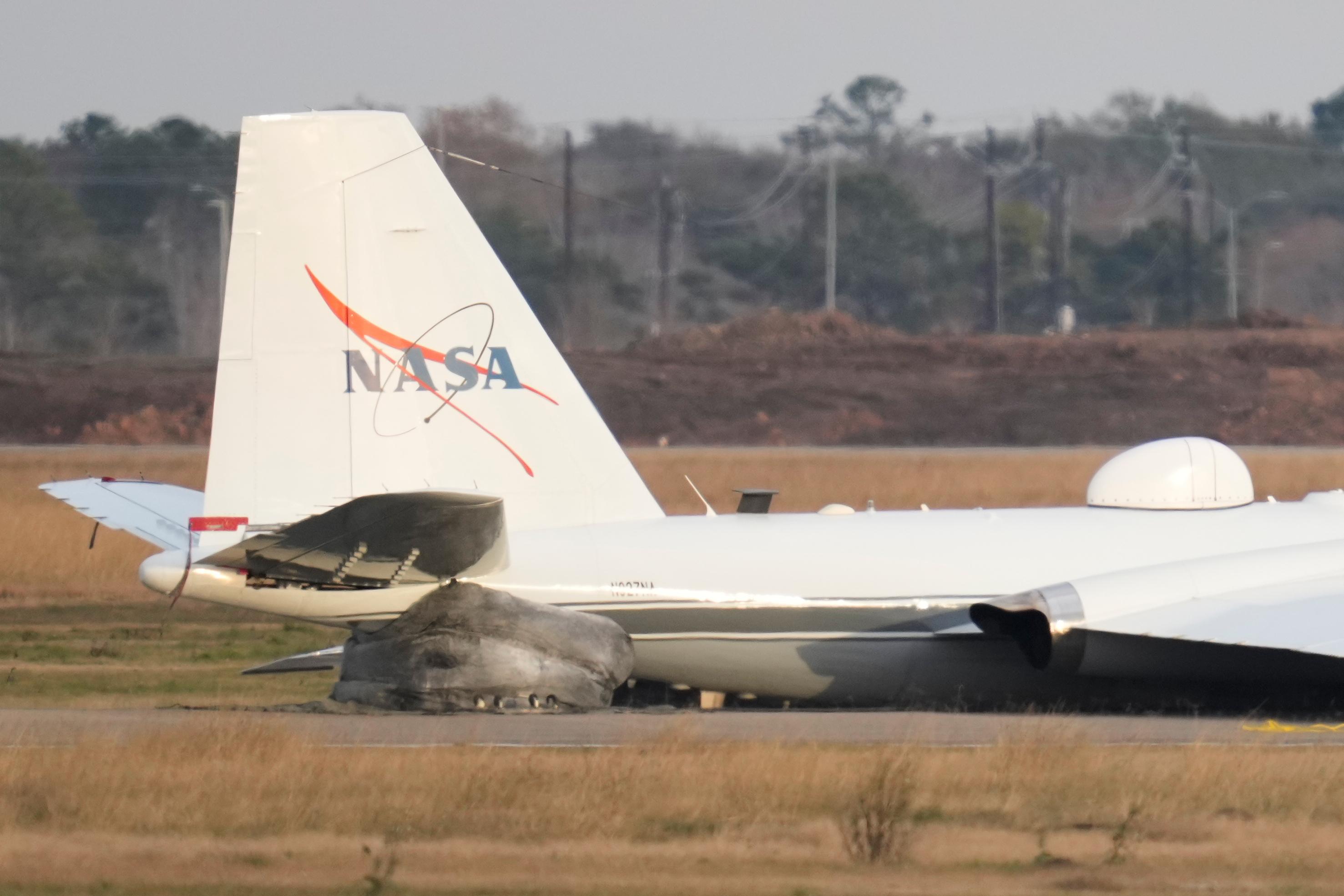 A NASA aircraft sits near a runway at Ellington Airport...