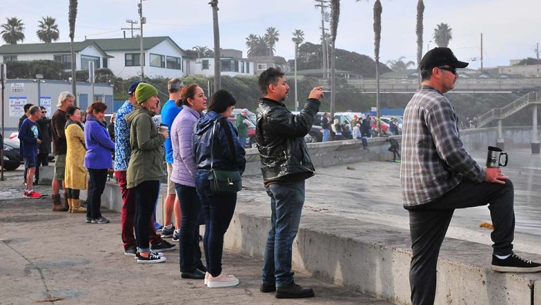 People line up along the Ocean Beach sea wall to watch the king tides slam into the pier early at high tide.
