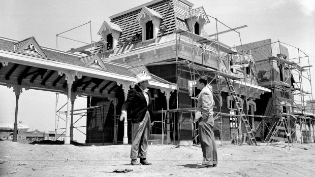 Walt Disney tells a visitor, Associated Press' Bob Thomas, where the two Disneyland trains will stop to take on passengers for the trip around the grounds. Railway Station in the background will be the first sight of Disneyland for visitors. The planning, design and construction of Disneyland is among the topics covered in the new docuseries "The Imagineering Story." (File photo by the Associated Press)