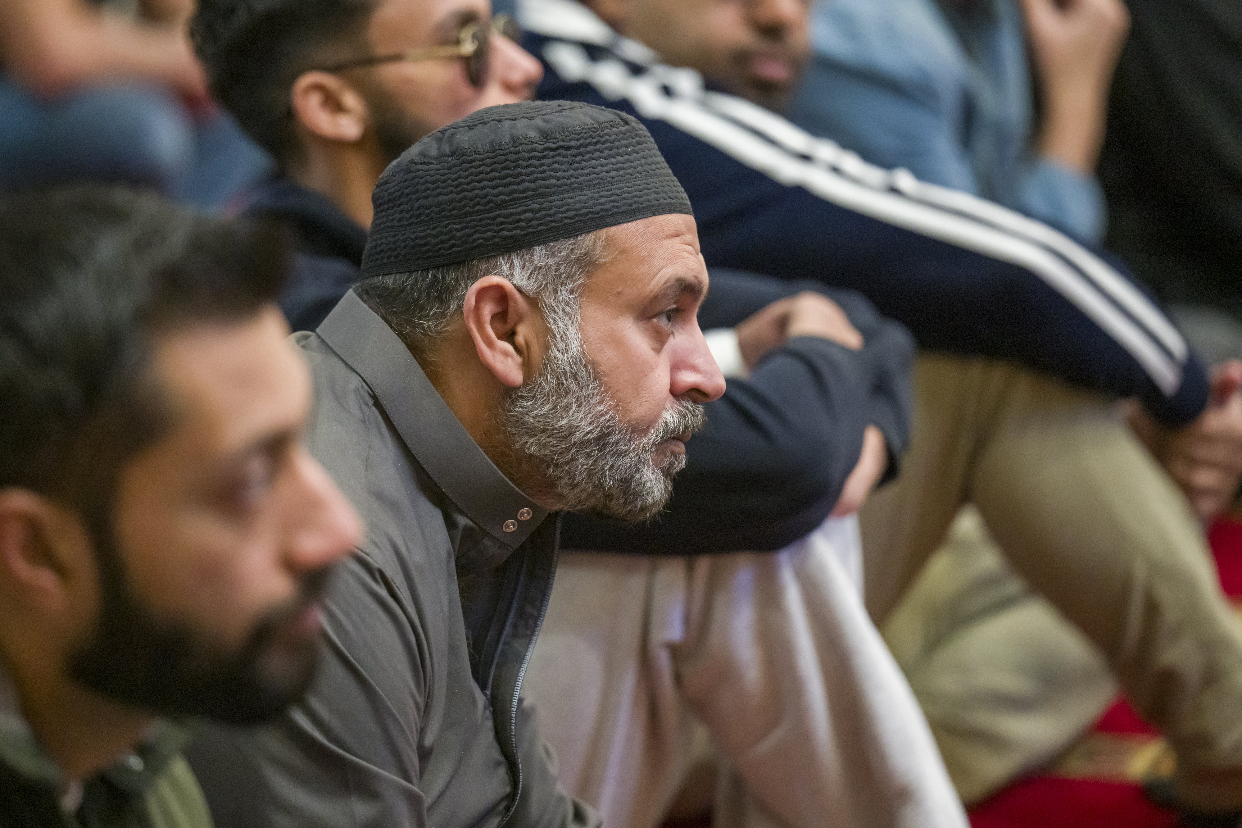 Men listen to a sermon from Imam Fayaz Nawabi at...