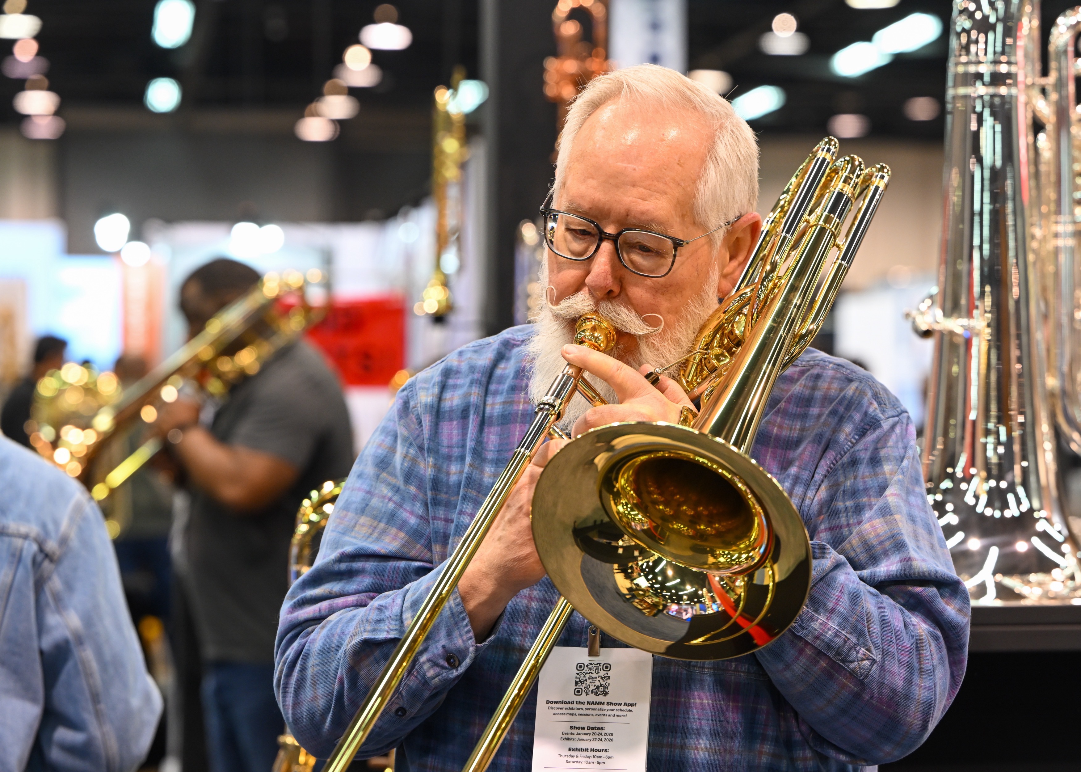 Music instructors Robert Anderson tries out a bass trombone during...