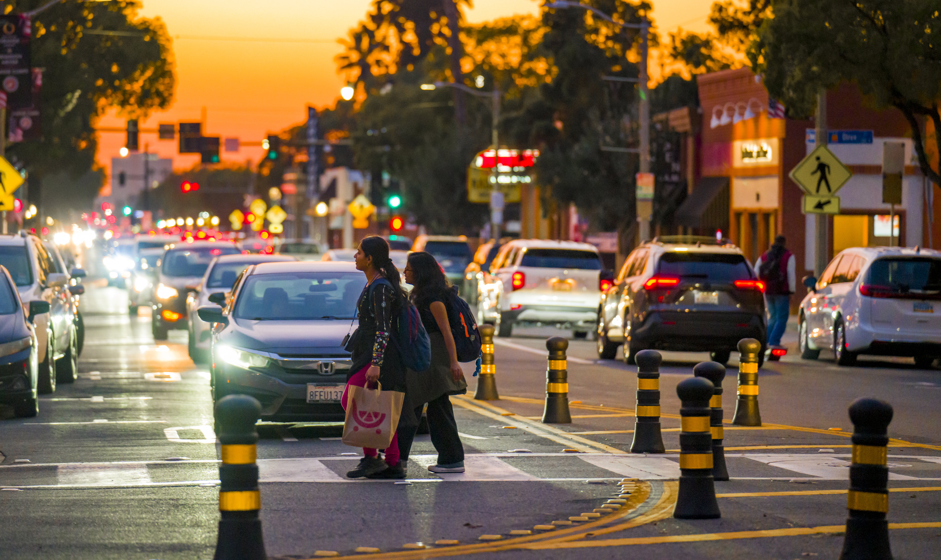 Pedestrians walk past traffic control bollards on Chapman Avenue on...