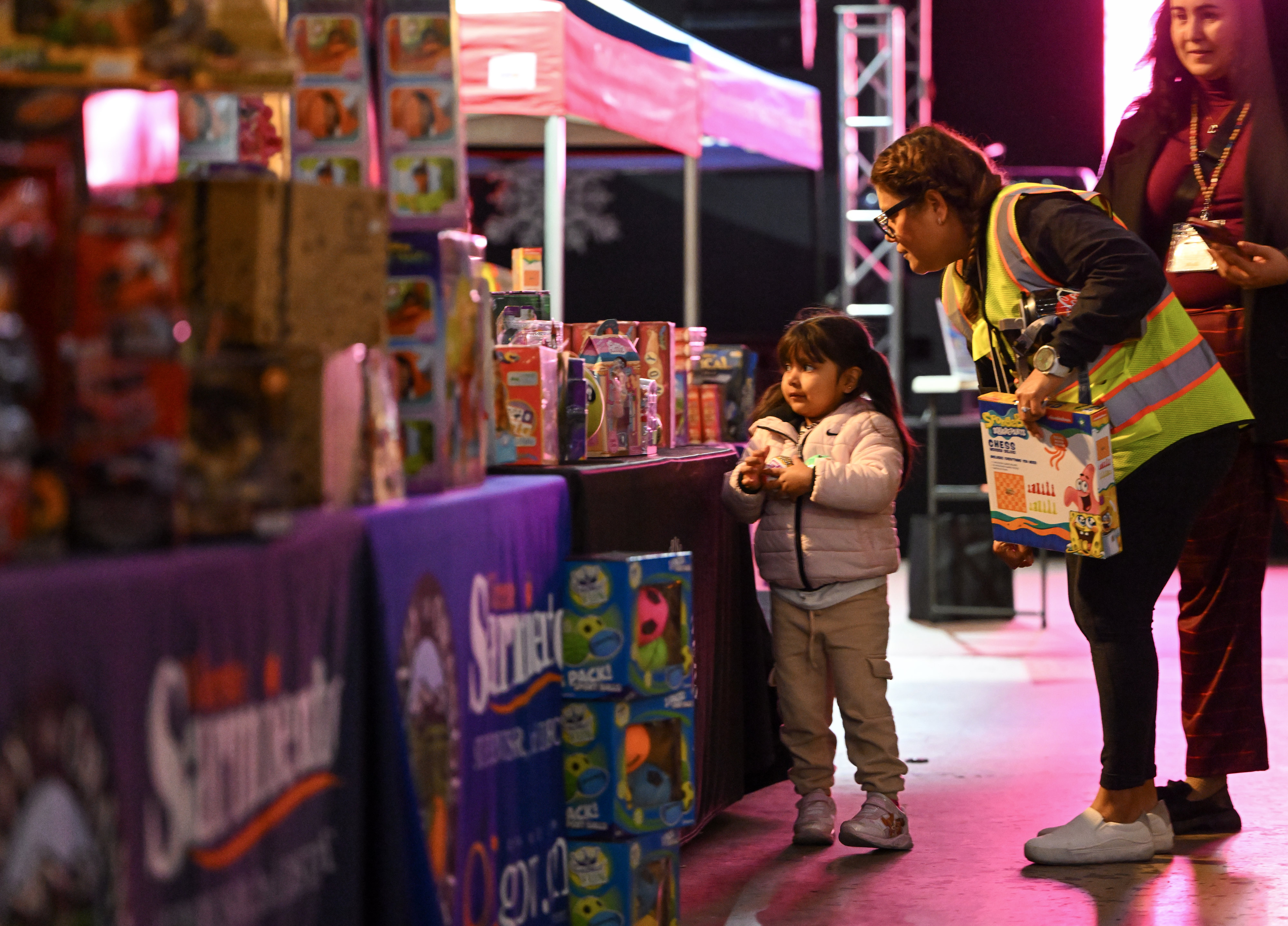 Colunteer Elsa Munsell helps Madison Cardoso, 4, choose a toy...