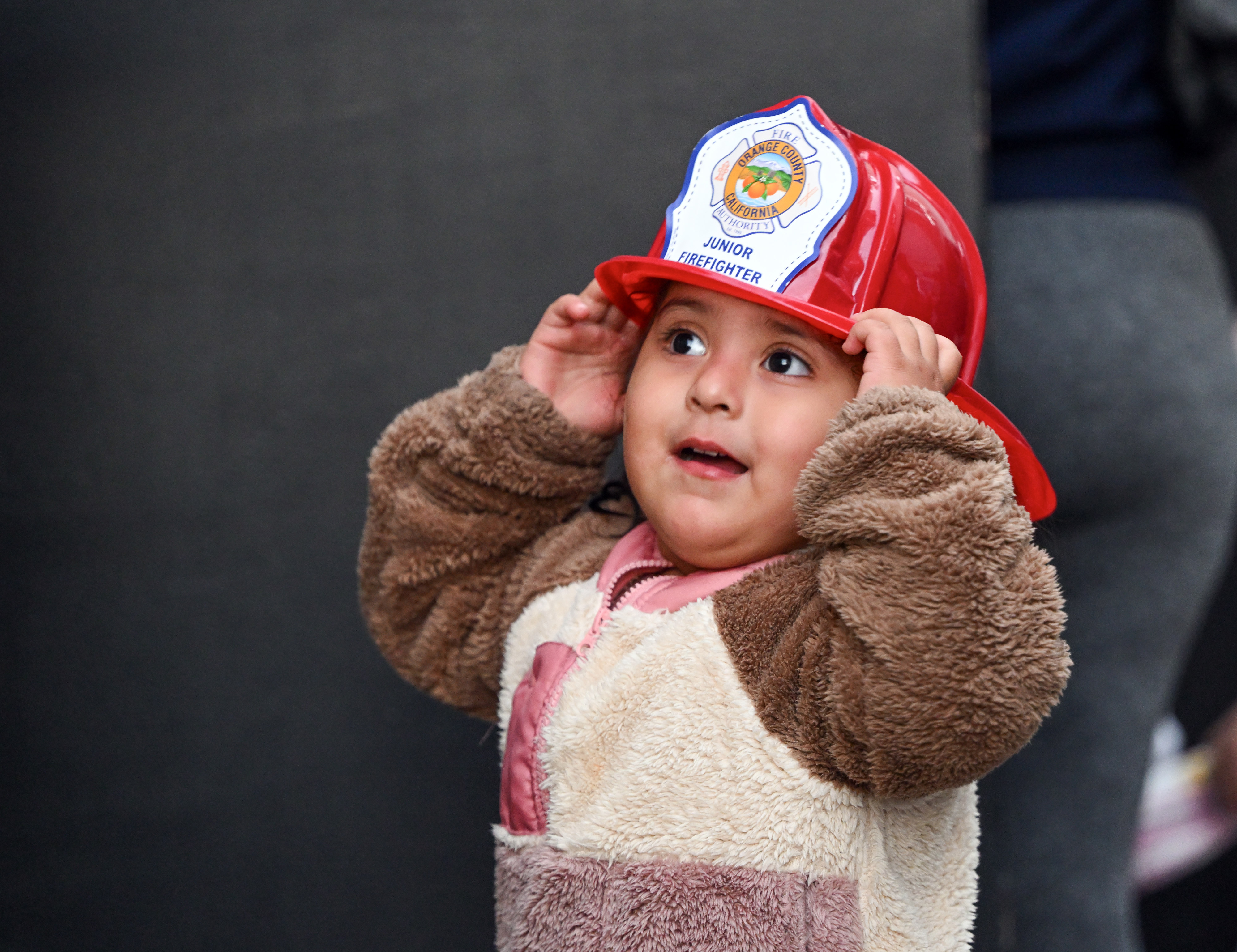 Arianna Anguiano holds on to her firemanâs helmet during the...