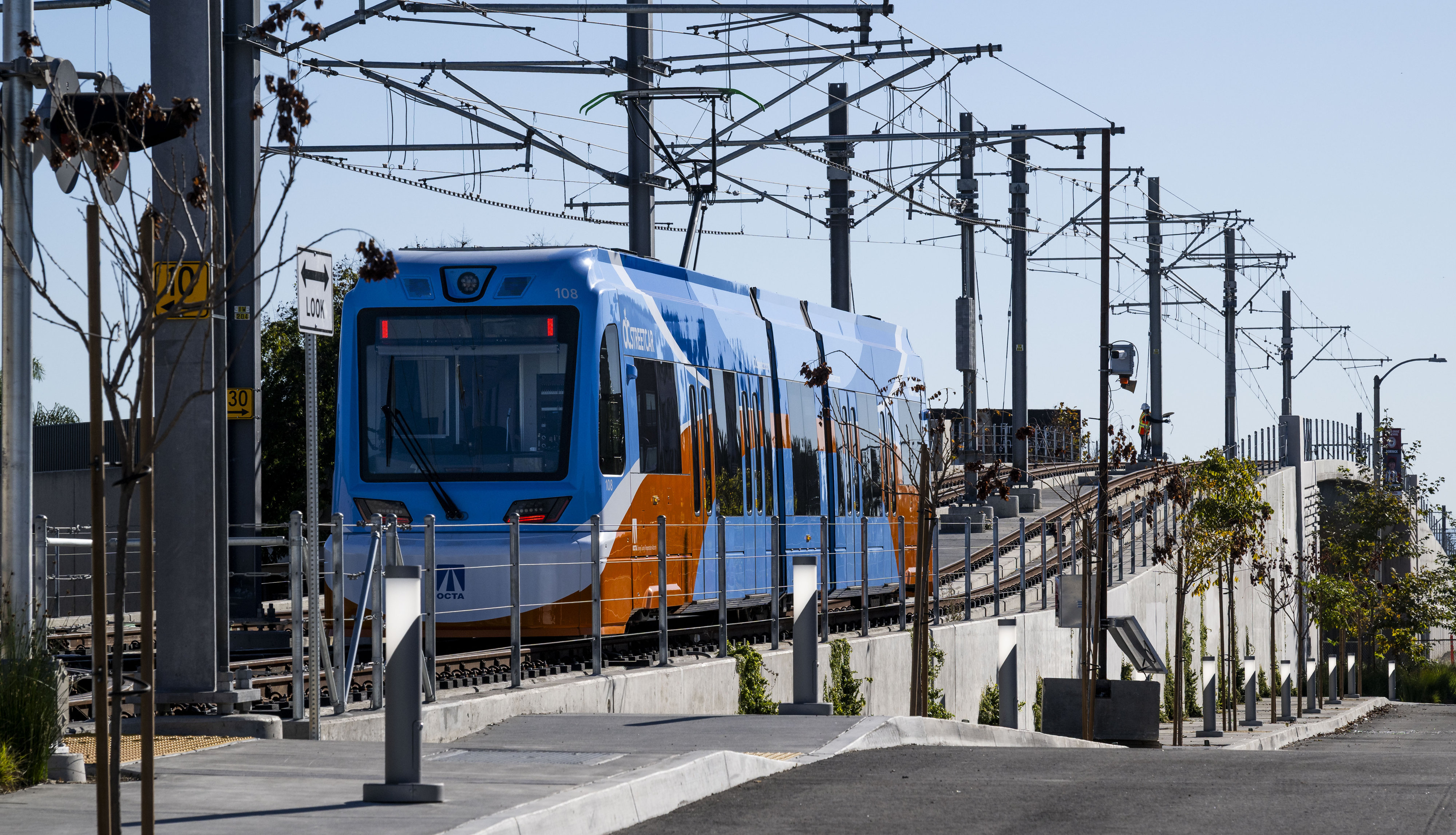An OC Streetcar train pulls away from a stop at...