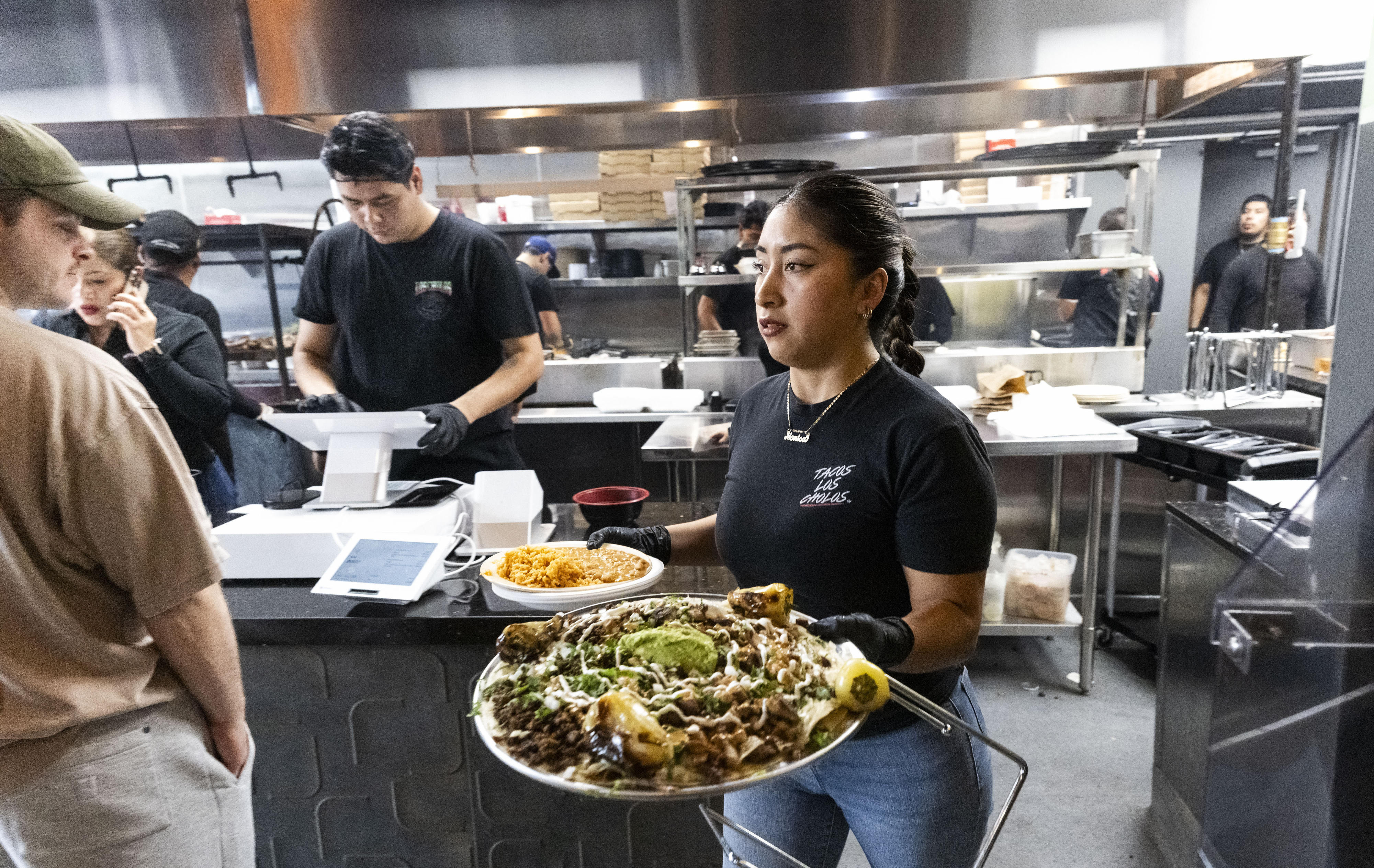 A waitress serves diners at Tacos Los Cholos in Santa...
