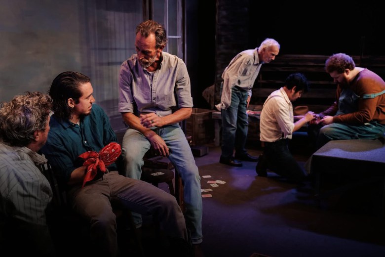 A group of men in work clothes under dim lighting on a stage