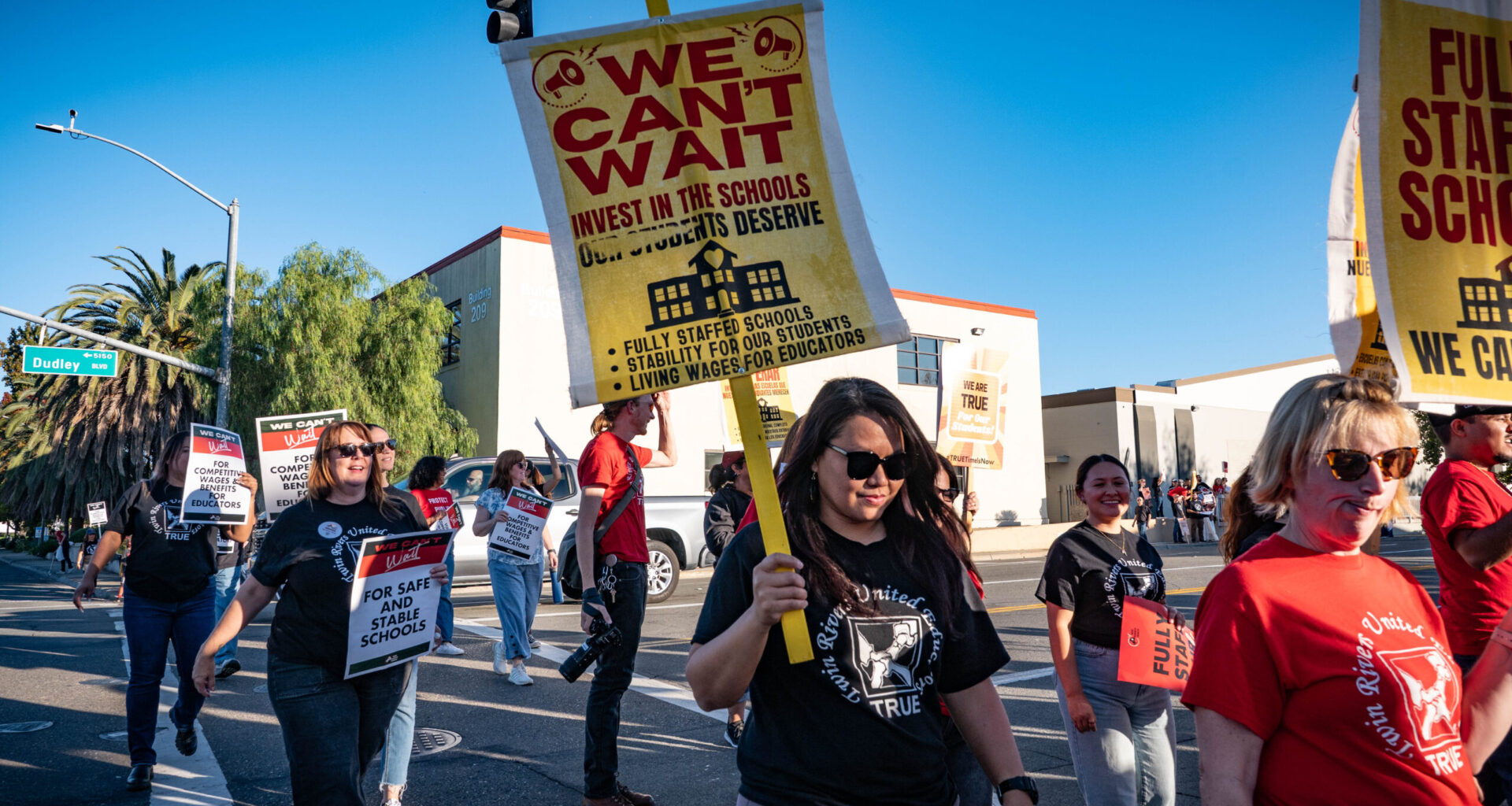 Teachers, parents, and community members cross the street to join the rally in front of Twin Rivers Unified School District on Tuesday, Oct. 21, 2025.