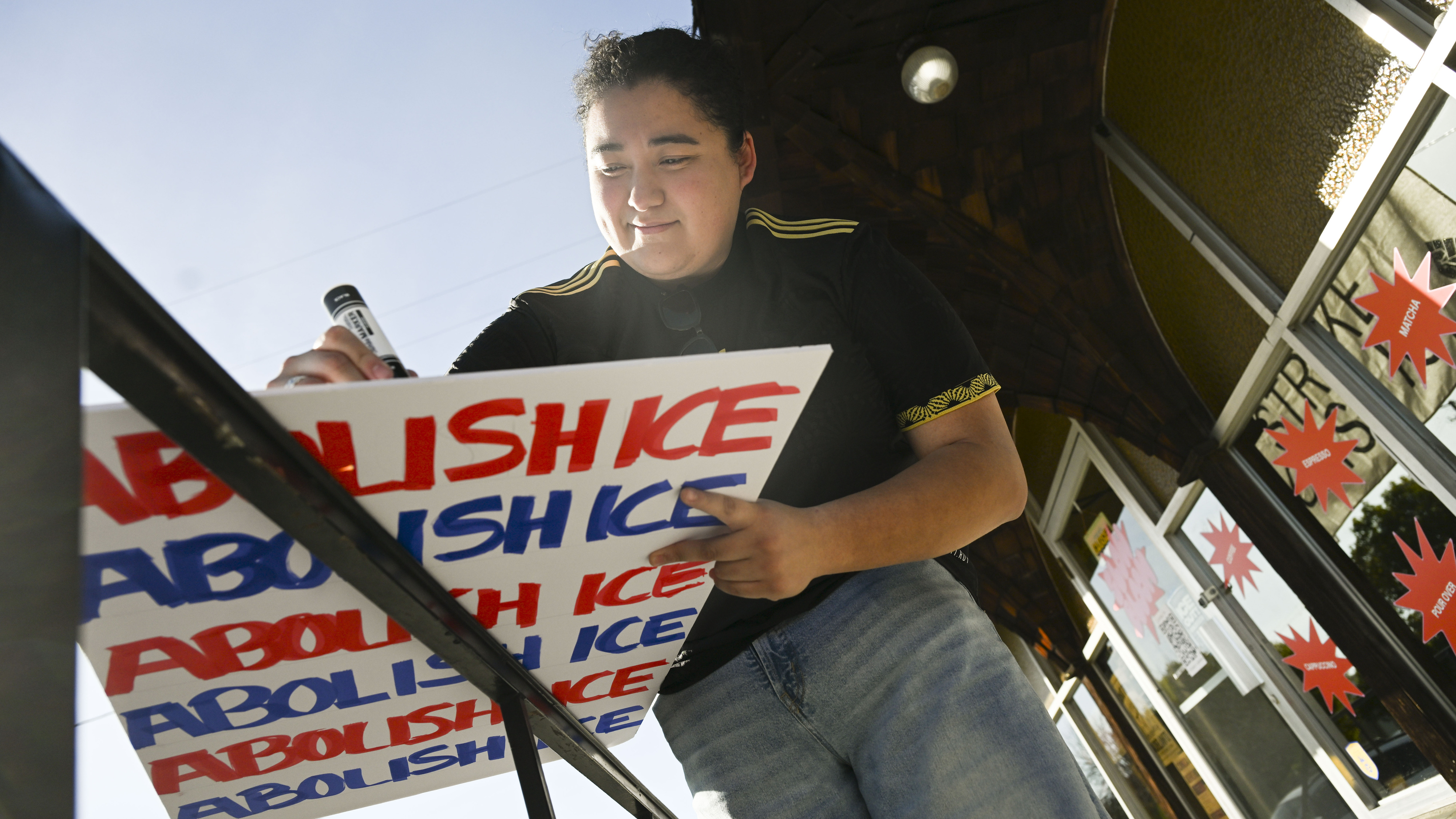 ICE protester Arleth Guerrero writes a message on a sign...