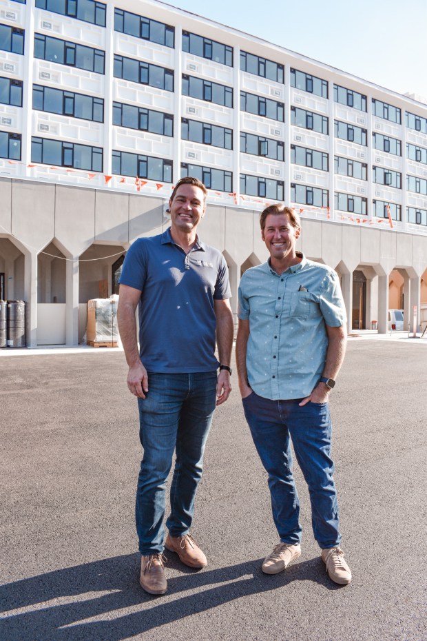 Robert Honer (left) of Ambient Communities and Jeff Cole of C2 Builders Group stand outside the former Consulate Hotel in Point Loma, which they are converting into the Celeste apartments. (C2 Builders Group)