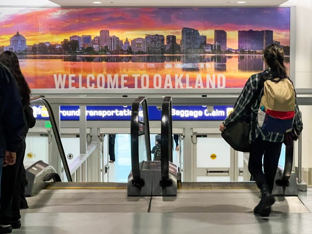 A traveler exits the Oakland San Francisco Bay Airport in Oakland, Calif., as the busy holiday travel season begins on Friday, Nov. 19, 2025. (Ray Chavez/Bay Area News Group)