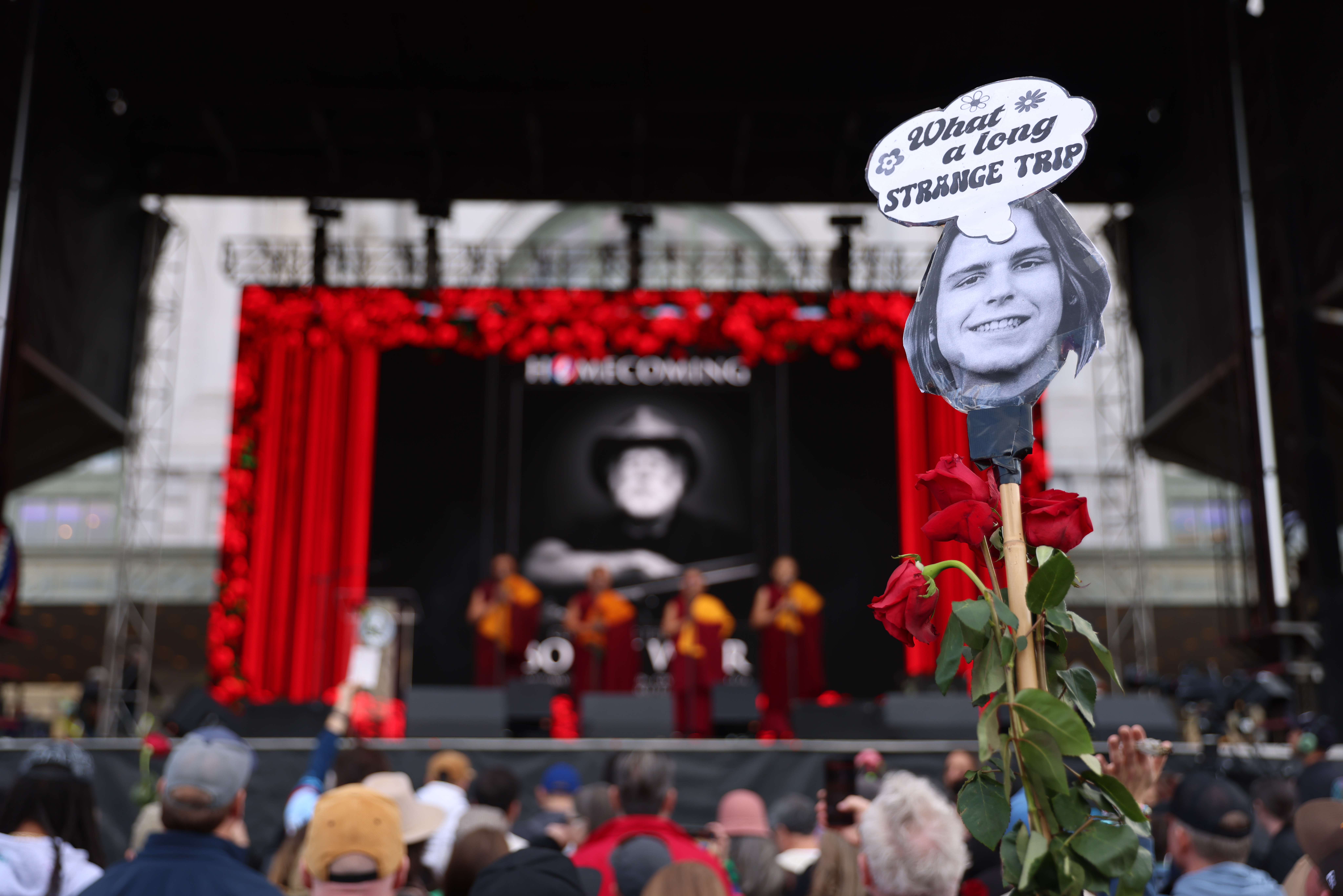 A Grateful Dead fan displays a sign and roses as...
