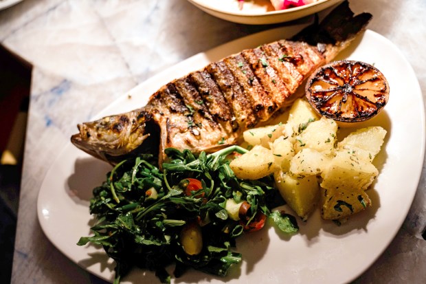 At the Elia restaurants, the Lavraki, a whole Mediterranean sea bass, is served with Greek potatoes and lemon-garlic sauteed spinach. (Photo courtesy of Elia)