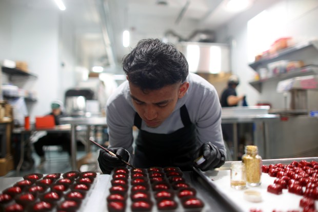 Chocolatier Jose Da Paz uses a brush to add gold flakes to heart-shaped bonbons at Casa de Chocolates on Jan. 27, 2026. The Oakland candy shop makes chocolates that are inspired by Mesoamerica, using ingredients from Latin and South America like mole, hibiscus, pumpkin seed and chile de arbol. (Aric Crabb/Bay Area News Group)