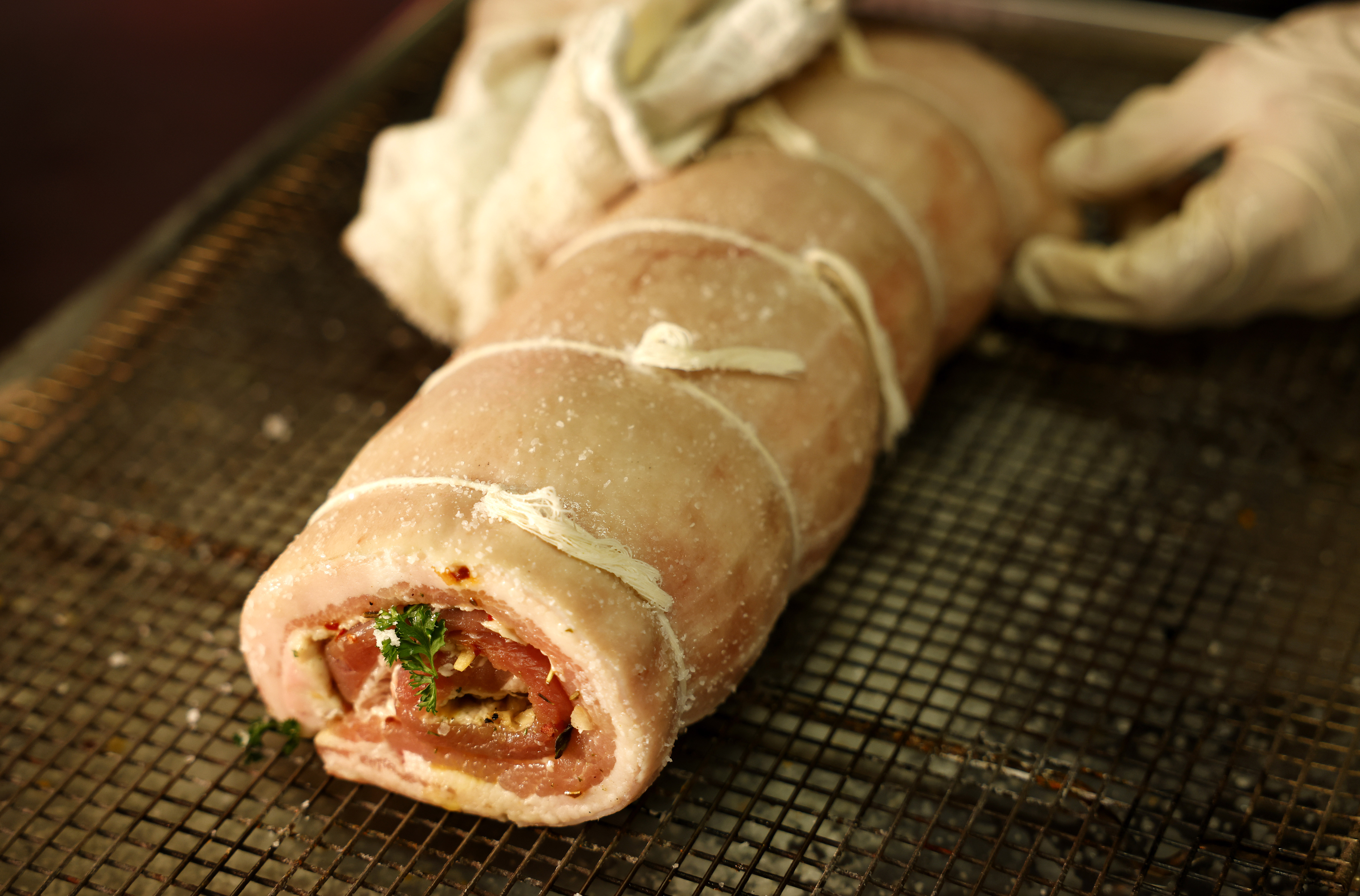 A pork belly is filled with herbs and spices and...