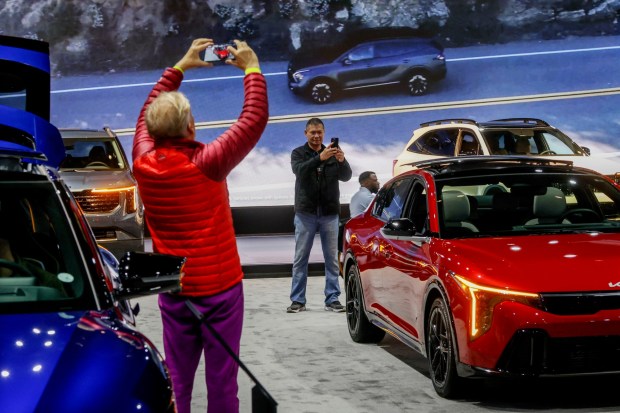 Visitors look over cars at the Kia booth at the San Diego International Auto Show at the Convention Center in Downtown on Saturday, Dec. 28, 2024. This year's event takes place Jan. 1-4 2026. (Photo by Sandy Huffaker for The San Diego Union-Tribune)