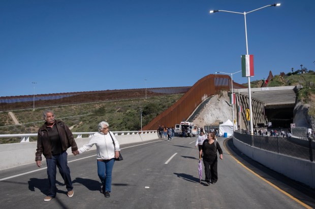 Abraham Nañez and Livia López walk along a section of a newly constructed elevated highway Friday in Tijuana. (David Maung / For The San Diego Union-Tribune)