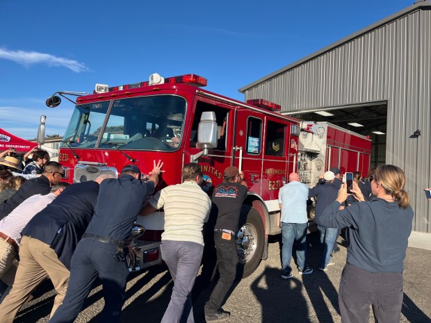 Participants at Wednesday's ribbon-cutting ceremony for the new, temporary Fire Station 1 participate in a traditional fire truck "push-in" event. (Barbara Henry / The San Diego Union-Tribune)