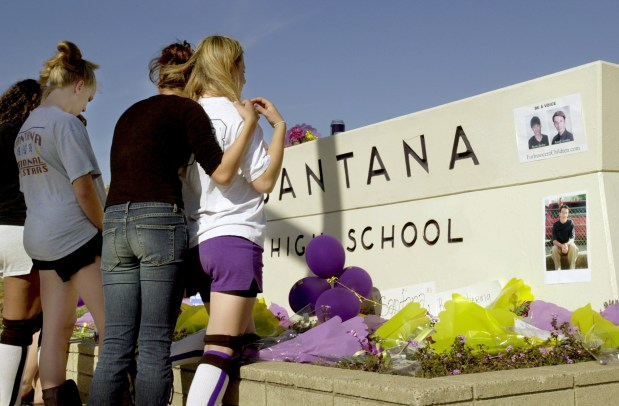 Santana High School students Natalie Koeberlein (cq, left), Amy Biggoni (cq, middle) and Amber Benz (cq, right) stop at the memorial set up at the front of Santana High School.  Today marks the 1 year anniversary when Andy Williams, another Santana HS student went on a shooting spree killing Bryan Zuchor and Randy Gordon.  (Nelvin C. Cepeda / UT file)