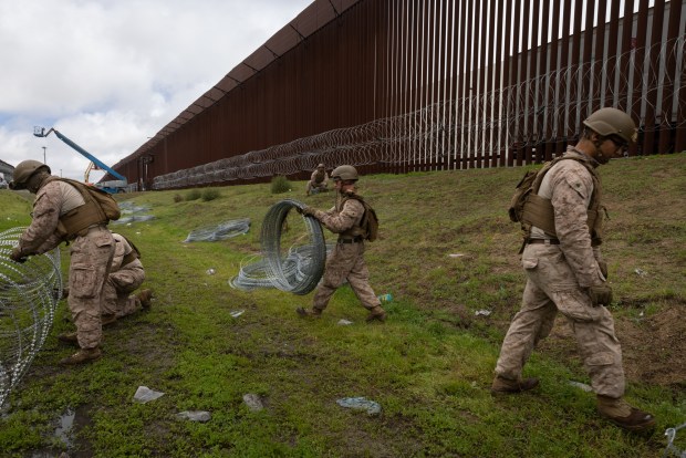 U.S. Marine Corps Task Force Sapper adds concertina wire to the U.S.-Mexico border walls on March 12 in Otay Mesa. (Ana Ramirez / U-T file)