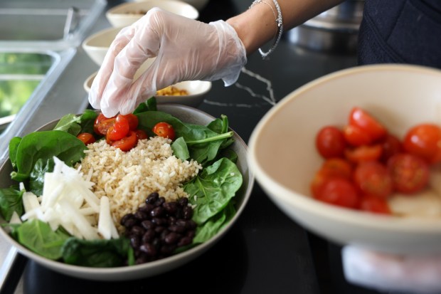 Jacqueline Gaistman adds cherry tomatoes to the Sprout and Grain Salad With Chickpeas and Chorizo. (Hayne Palmour IV / For The San Diego Union-Tribune)
