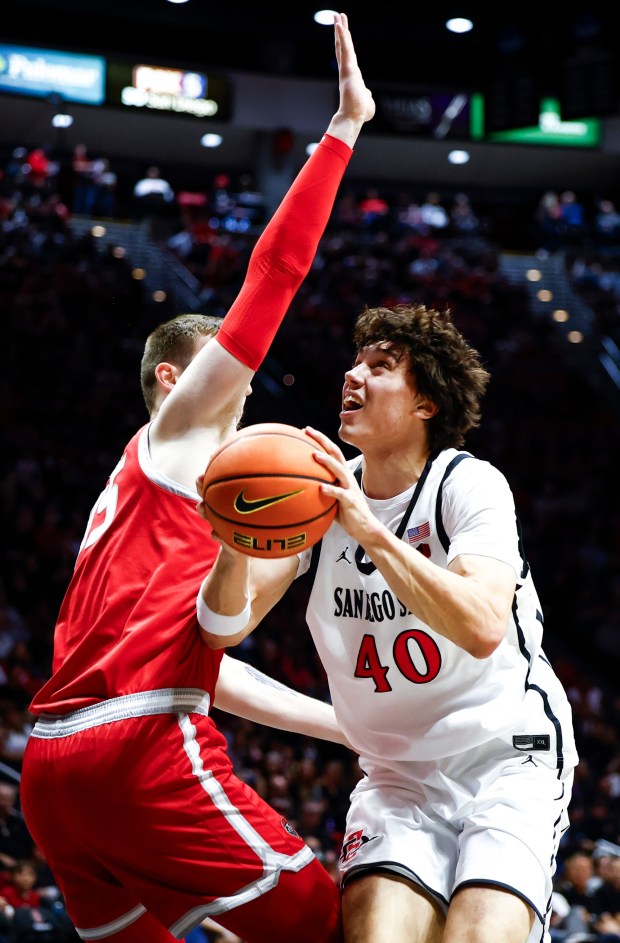 SDSU forward Miles Heide drives against New Mexico's JT Rock in the Aztecs' 83-79 win at Viejas Arena on Saturday. (Meg McLaughlin / The San Diego Union-Tribune)