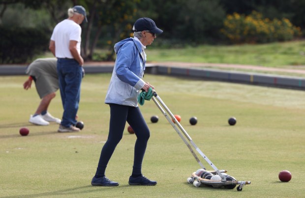 SAN DIEGO, CA - January 03, 2026: San Diego Lawn Bowling Club Treasurer, Kathleen Wageman, who is also in charge of the club's membership, gathers up balls as she and other members play at Balboa Park in San Diego on Saturday, January 03, 2026. (Hayne Palmour IV / For The San Diego Union-Tribune)