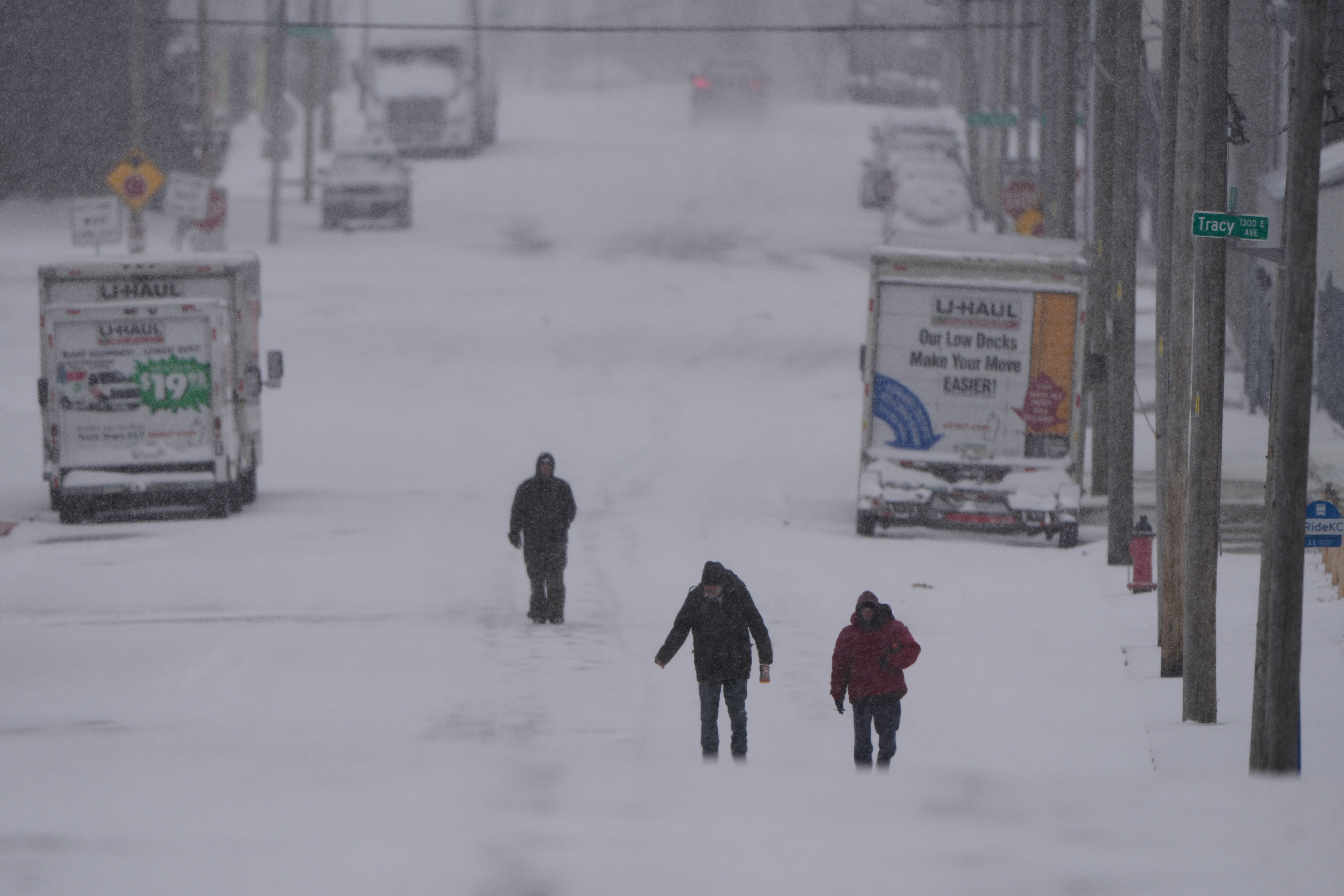 People walk on a snow-covered street as a winter storm...