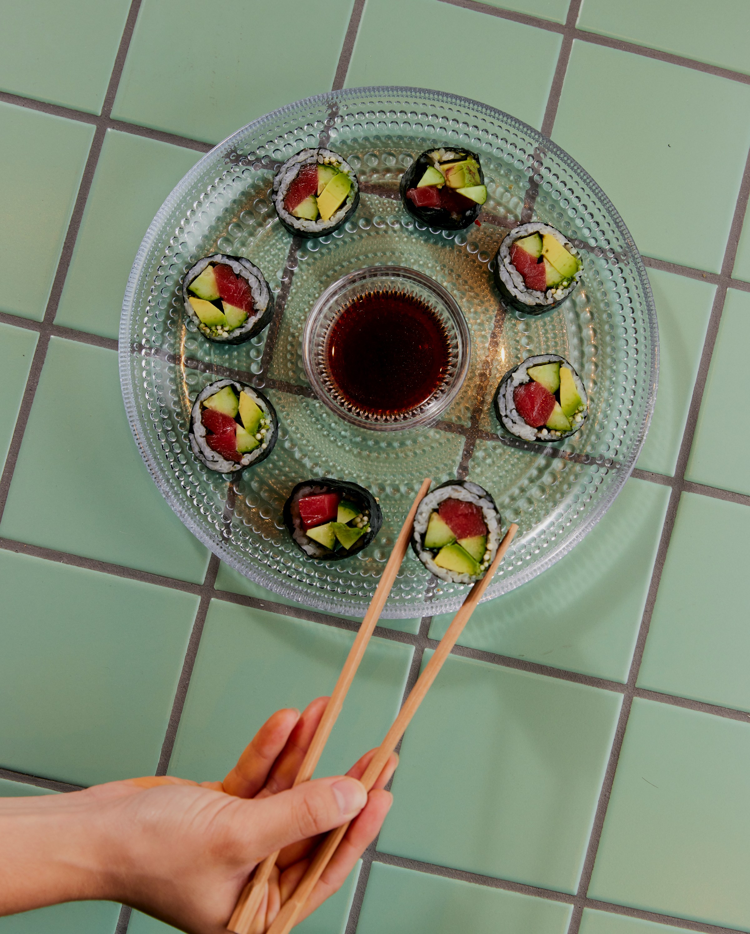 Hand with chopsticks picking up a piece of tuna gimbap