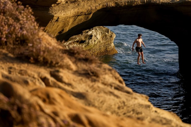 A person jumps off the cliffs at Sunset Cliffs on Thursday, July 31, 2025 in San Diego, CA.