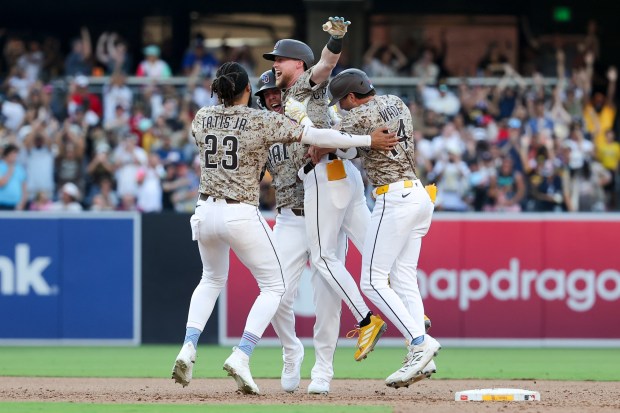 Jake Cronenworth #9 of the San Diego Padres is congratulated by Fernando Tatis Jr. #23, Gavin Sheets #30 and Tyler Wade #14after hitting a walk-off single against the Texas Rangers during the tenth inning at Petco Park on Friday, July 4, 2025 in San Diego, CA. (Meg McLaughlin / The San Diego Union-Tribune via Getty Images)